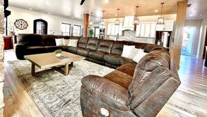 A spacious living room with a large sectional sofa, a coffee table, and a fireplace. - Grand Gathering Retreat-Private Heated Pool-Mini Golf-Sand Hollow ATV Mecca-Zion (Hurricane)