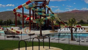 A water park with a large water slide, a pool area, and a view of mountains in the background. - Grand Gathering Retreat-Private Heated Pool-Mini Golf-Sand Hollow ATV Mecca-Zion (Hurricane)