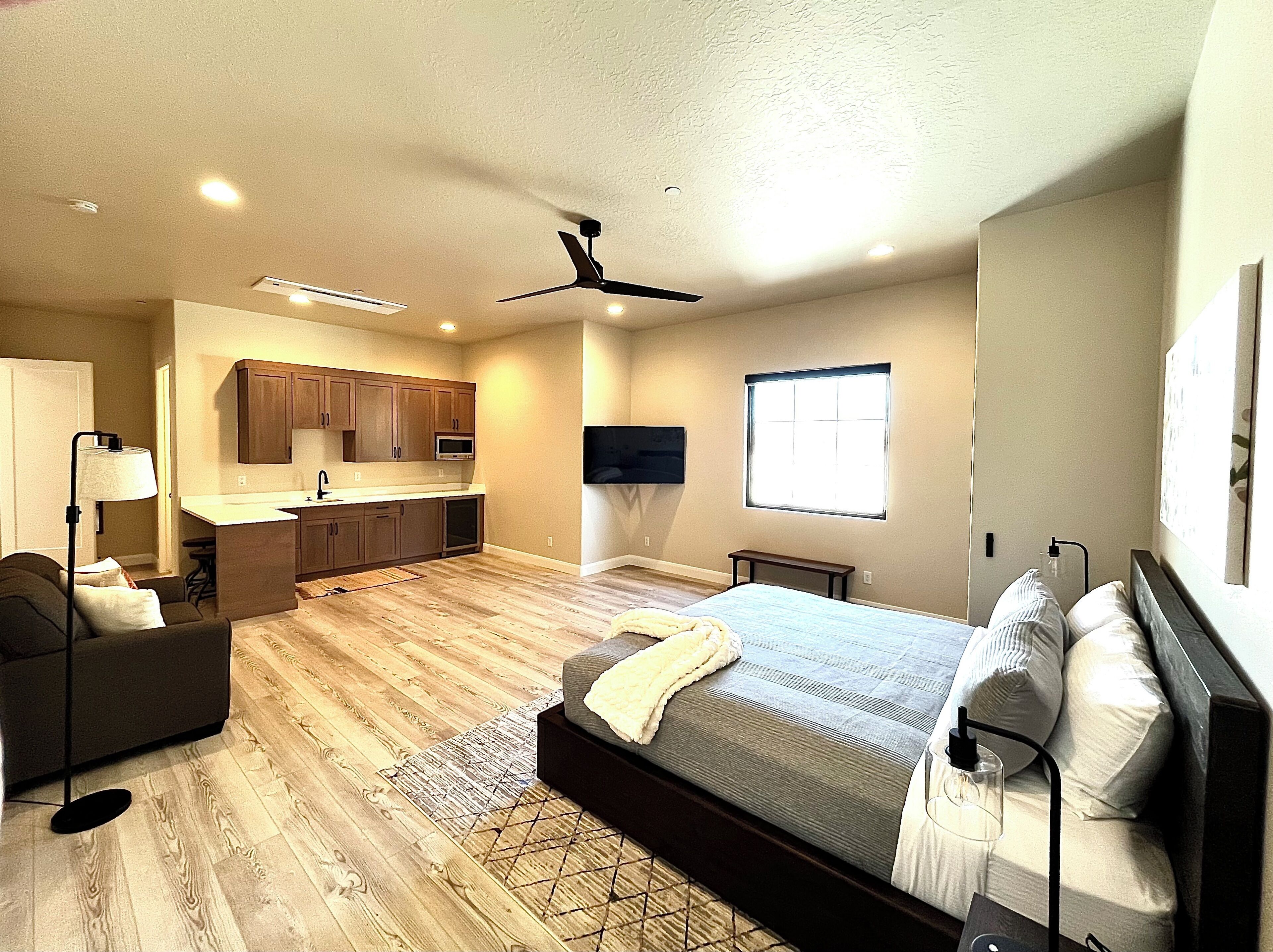 Un dormitorio moderno con una cama grande, un escritorio y una kitchenette.