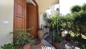 A wooden door, a potted plant, a large vase, and a metal gate. - Villa Carini Holiday House by the Sea and Jacuzzi pool (Carini)