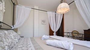 A bedroom with a bed, a bedside table, a lamp, a chair, and a hanging light fixture. - Villa Carini Holiday House by the Sea and Jacuzzi pool (Carini)