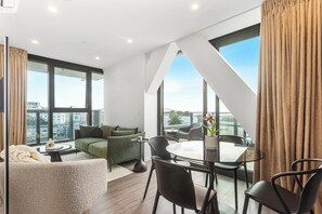 Ein modernes Wohnzimmer mit einem grünen Sofa, einem runden Tisch und schwarzen Stühlen.