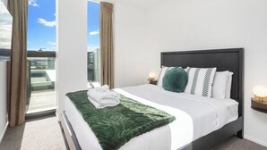 Une chambre d’hôtel moderne avec un grand lit, une vue sur la ville et un balcon.