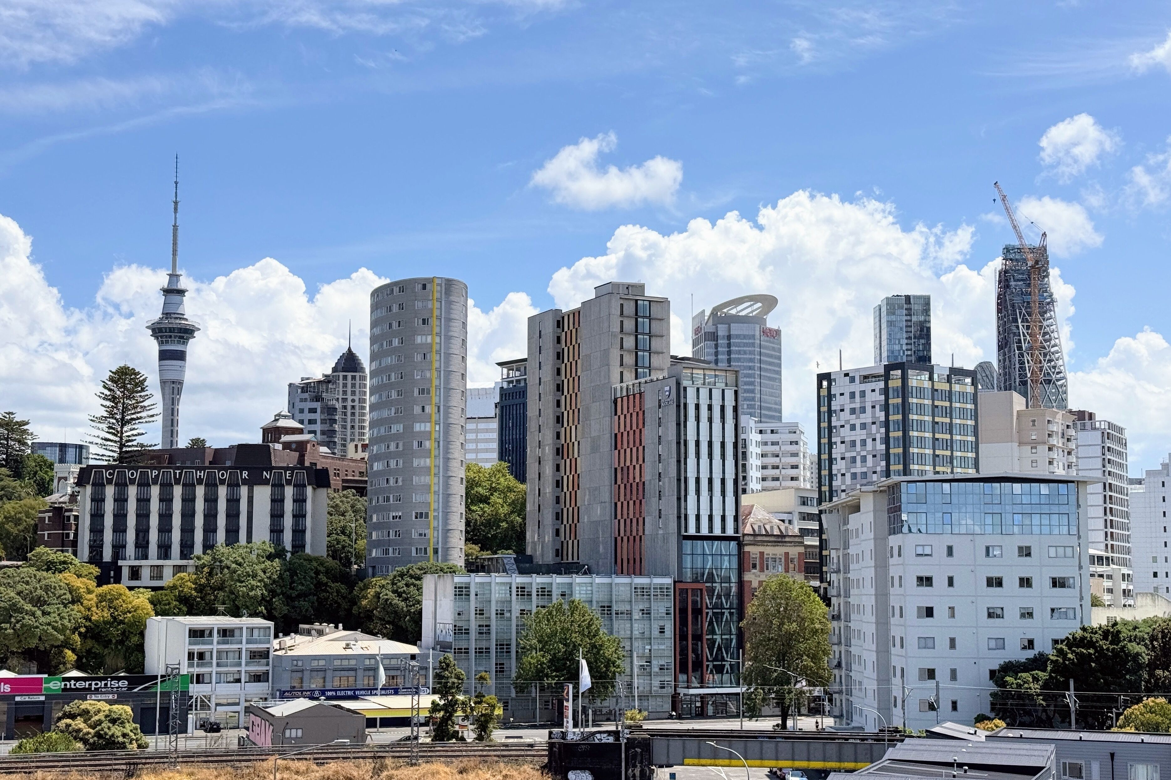A city skyline with modern high-rise buildings, a prominent tower, and a mix of commercial and residential structures.