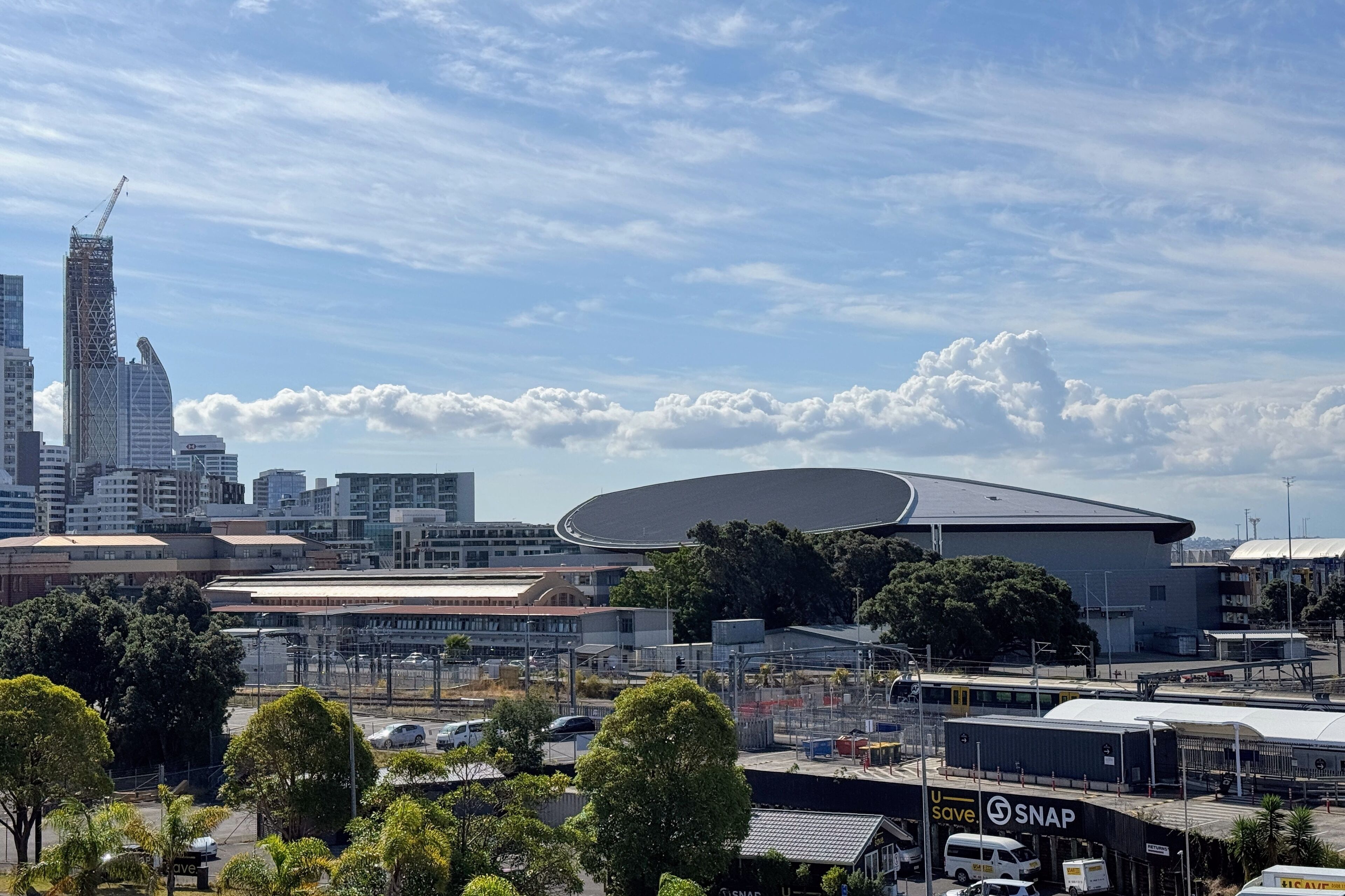 Paisagem urbana com edifícios modernos, um estádio grande e uma área de estacionamento.