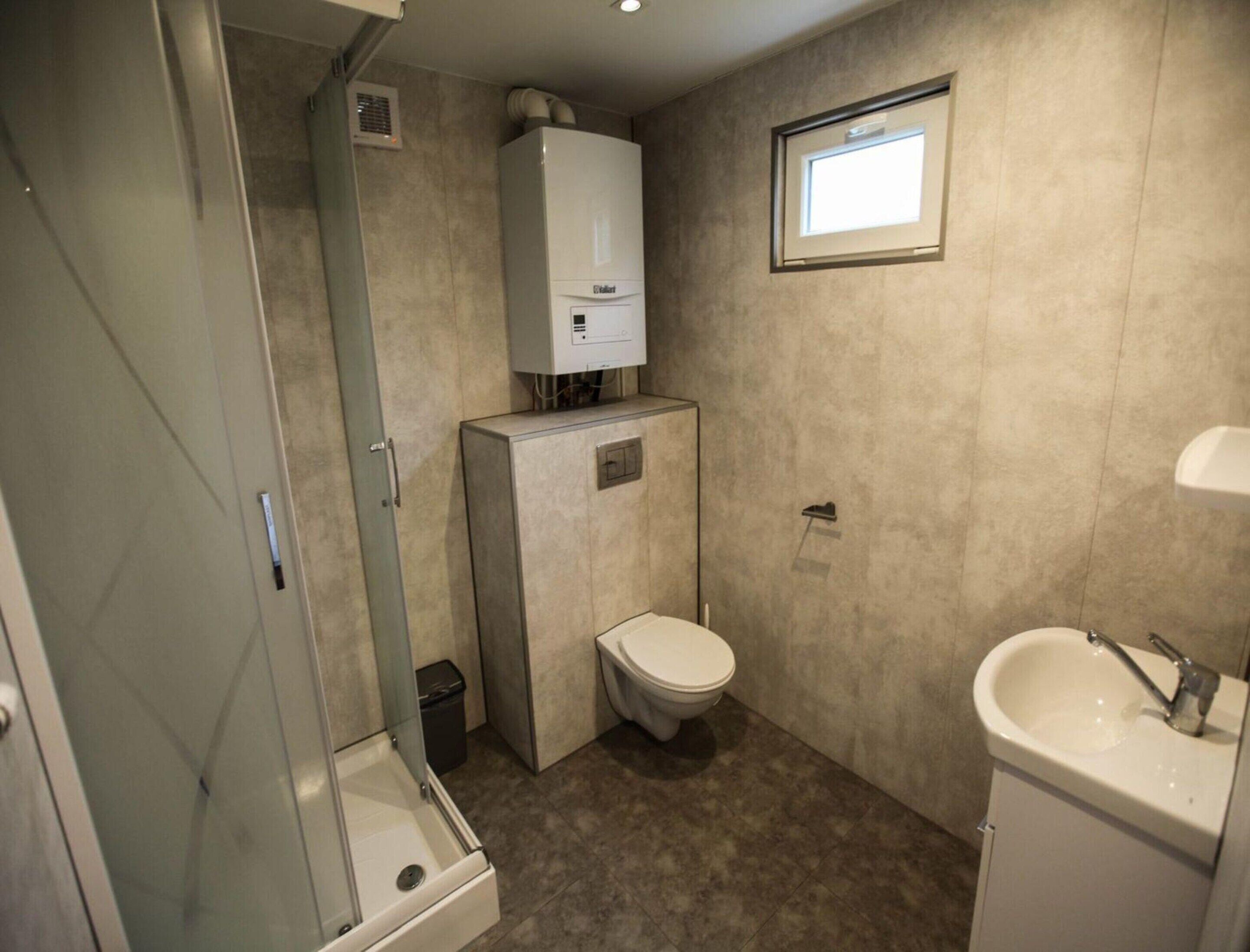 A compact bathroom with a shower, toilet, and sink.