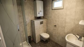 A compact bathroom with a shower, toilet, and sink.