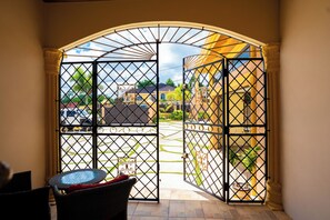 An open gate leading to a courtyard with a view of a building and parked cars. - Elegant apartment with WiFi in safe , private area in Mandeville (Mandeville)