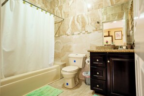 A bathroom with a toilet, bathtub, and a vanity with drawers. - Elegant apartment with WiFi in safe , private area in Mandeville (Mandeville)