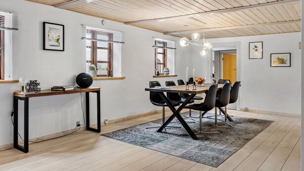 Een eethoek met een houten tafel, zwarte stoelen en een moderne hanglamp.