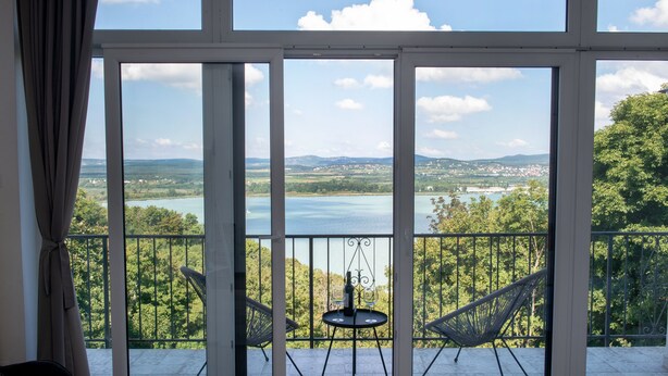 Un balcón con vistas a un lago y follaje circundante.