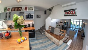 Una cocina amplia con una isla central, un comedor con mesa de madera y una sala de estar con sofá y mesa baja.