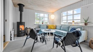 A cozy living room with a fireplace, a sofa, two chairs, and a table.