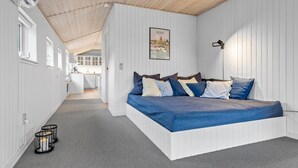 A bedroom with a bed, a nightstand, a lamp, and a painting on the wall.