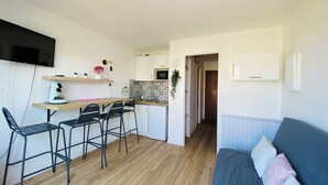 A compact living space with a kitchenette, a dining area with a table and chairs, and a sofa in the living area.