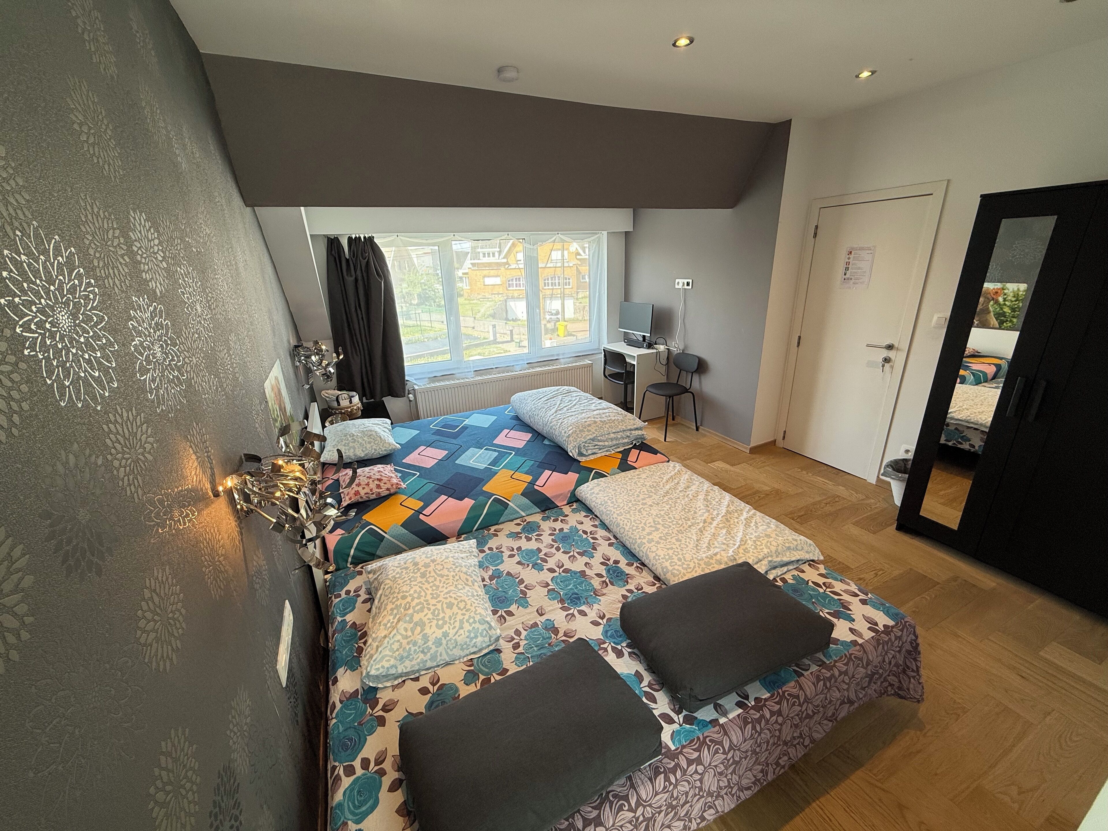 A bedroom with a large bed, a desk, and a chair.