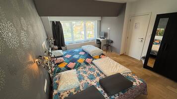A bedroom with a large bed, a desk, and a chair.