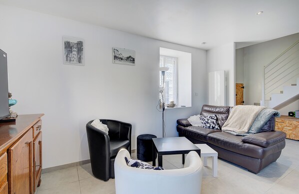 A modern living room with a sofa, armchair, and coffee table. There is a window with a view of a staircase. - Spacious house - sleeps 6 - ideal location - near the highway (Monnaie)