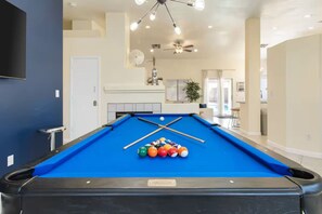 A pool table with balls, a ceiling fan, and a fireplace. - Quiet 4 BD Home w/ Pool (North Las Vegas)