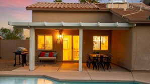 A covered patio with a pool, a barbecue grill, and a dining area with chairs and a table. - Quiet 4 BD Home w/ Pool (North Las Vegas)
