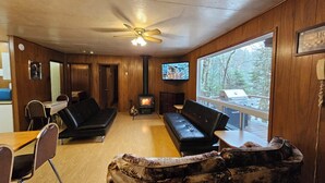 A cozy living room with a fireplace, a sofa, a dining table with chairs, and a television. - Family Reunion Cottage - Can sleep 16+  - Includes Motor Boat, Canoe, AC - Wi-Fi (Britt)