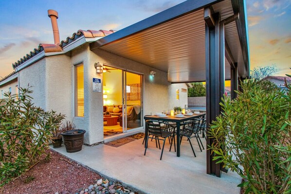 A house with a covered patio, a pool, and a dining area.