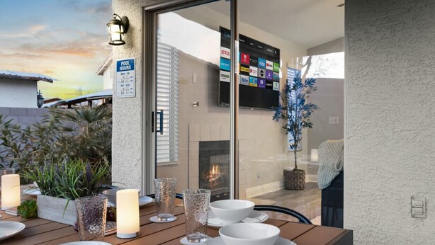 A dining area with a table set for four, a fireplace, and a TV screen displaying various streaming services. - Modern 5 BD Home w/ Smart TV and Ping Pong (North Las Vegas)