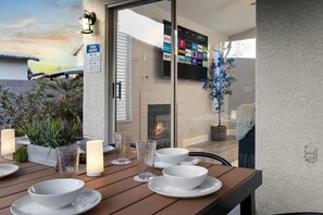 Un coin repas avec une table dressée pour quatre personnes, une cheminée et un écran de télévision diffusant différents services de streaming.