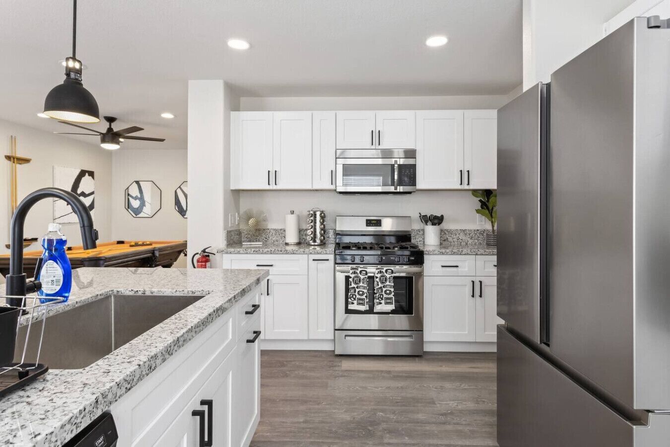 A modern kitchen with white cabinets, stainless steel appliances, and a granite countertop.