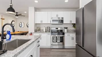 A modern kitchen with white cabinets, stainless steel appliances, and a granite countertop.