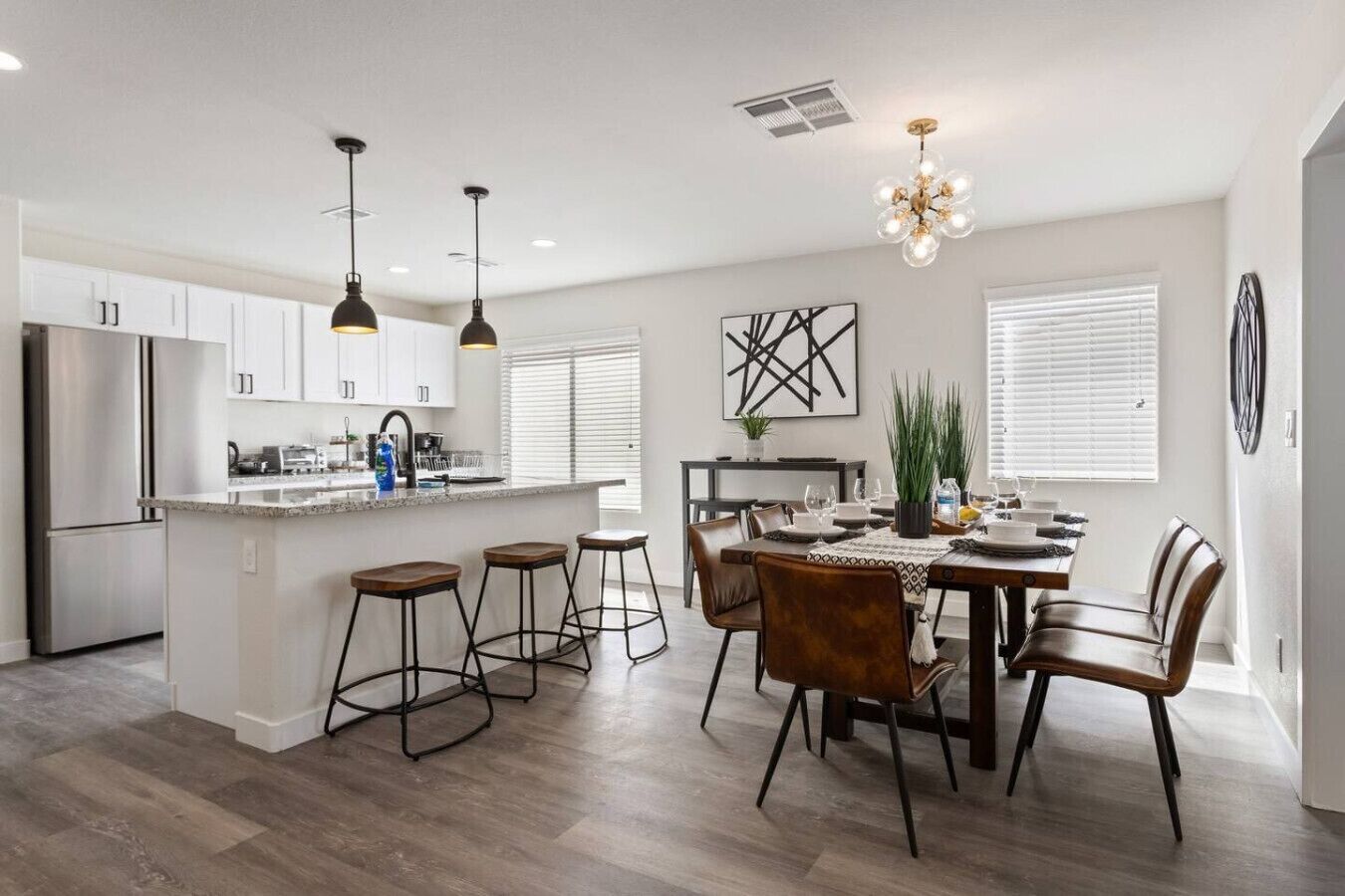 A modern kitchen with white cabinets, stainless steel appliances, and a central island with bar stools.