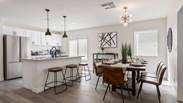 A modern kitchen with white cabinets, stainless steel appliances, and a central island with bar stools.