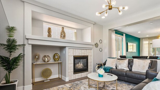A living room with a fireplace, a sofa, a coffee table, and a chandelier.