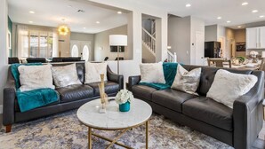 A modern living room with two black leather sofas, a round coffee table, and a patterned rug.