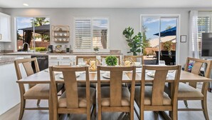 A modern kitchen with a dining area, large windows, and a view of the outdoors.