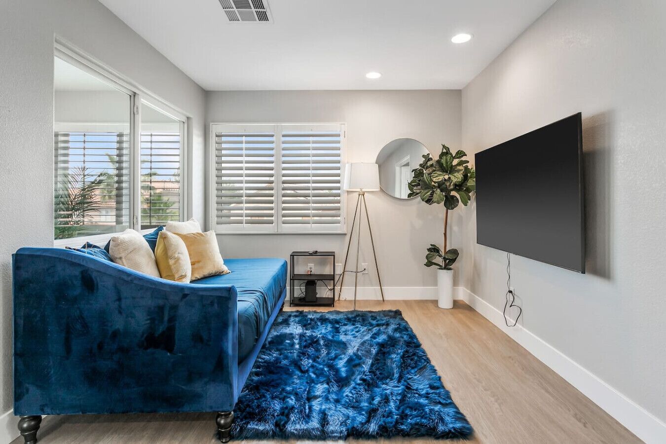 A modern living room with a blue sofa, a large TV, and a floor lamp.