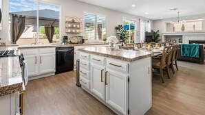 A spacious kitchen with white cabinetry, granite countertops, and a central island.