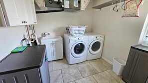 A laundry room with a washing machine, dryer, and a utility sink.