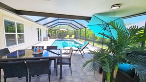 Un patio cubierto con piscina, mobiliario exterior y plantas en macetas.
