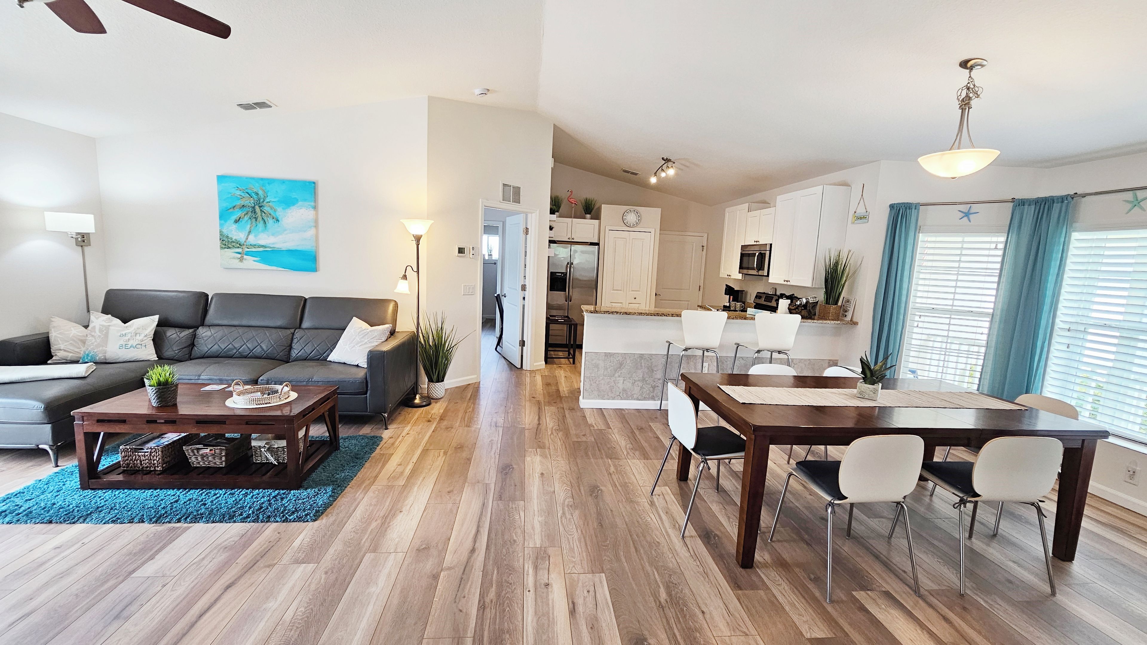 Ein modernes Wohnzimmer mit einer Couch, einem Couchtisch und einem Bild von einer Strandansicht.