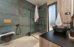 Ein modernes Badezimmer mit einer Duschkabine aus Glas, einem schwarzen Waschbecken mit Schale und einer Holz-Waschkommode.