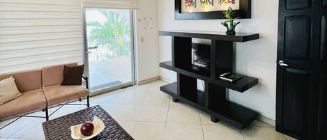 A modern living room with a sofa, a coffee table, a black entertainment unit, and a door.