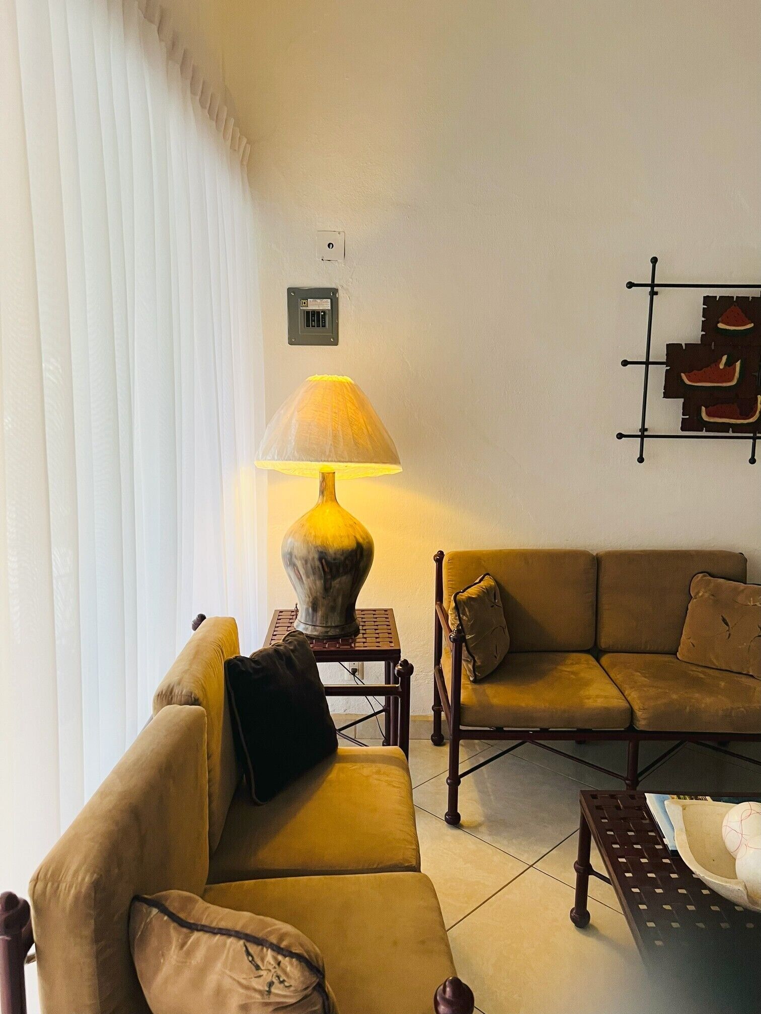 Una sala de estar con sofá, una mesa, una lámpara y una estantería de pared.