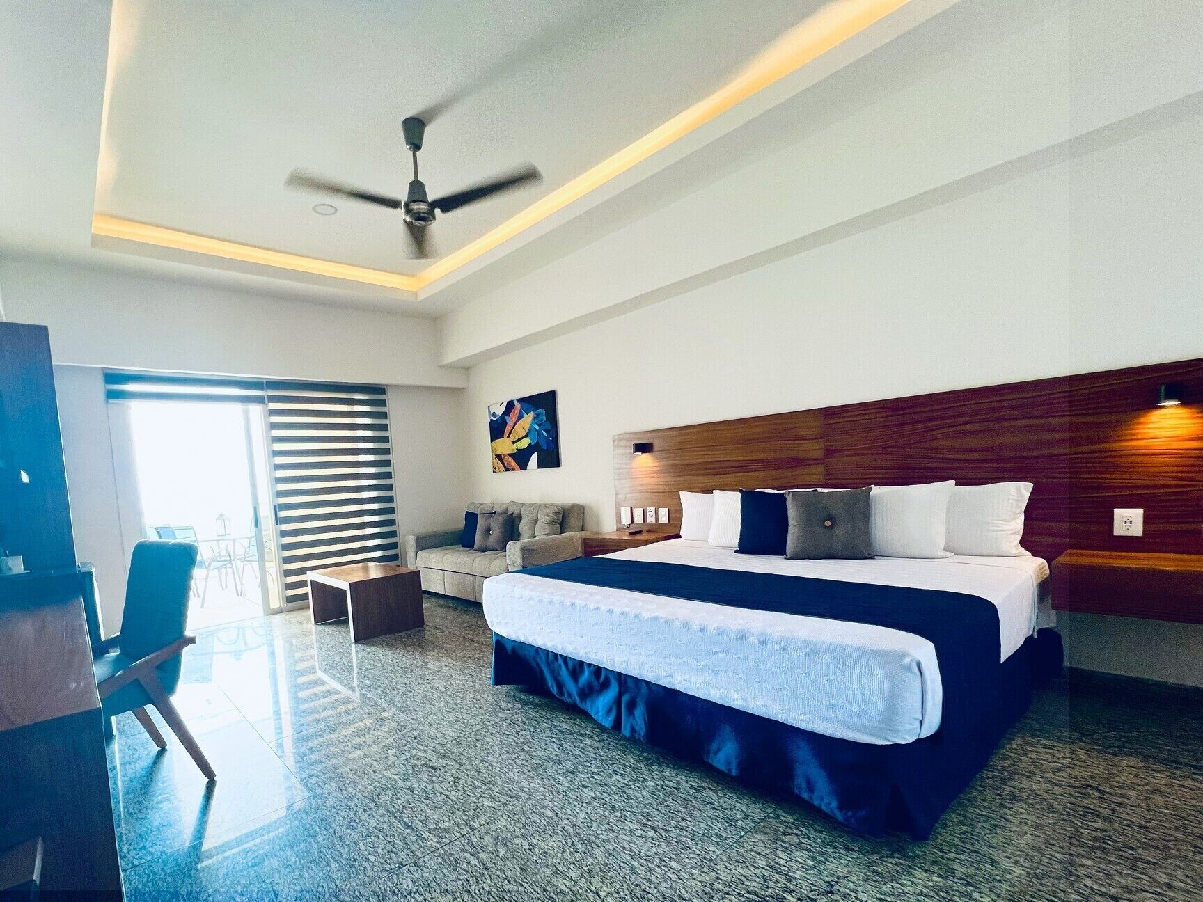 Una habitación de hotel moderna con una cama grande, un escritorio y una silla.