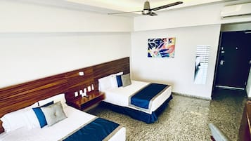 Ein Hotelzimmer mit zwei Betten, einem Deckenventilator, einem Bild an der Wand und einem Teppichboden.