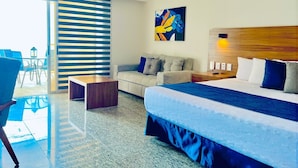 Una moderna camera d'hotel con un letto grande, un divano, un tavolino e un'area pranzo con sedie.