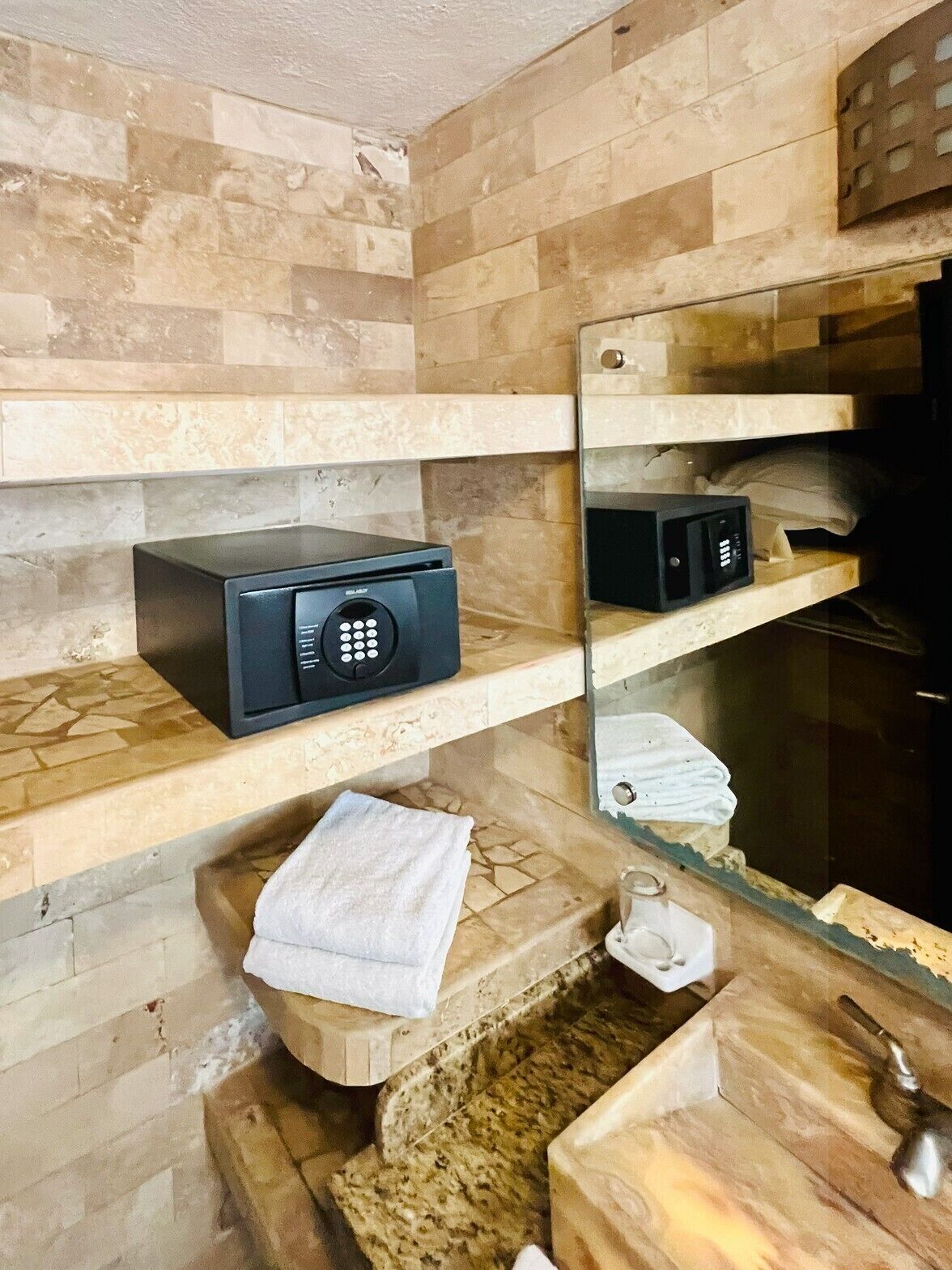 A bathroom with a stone wall, a black radio, a towel, and a sink with a metal faucet.