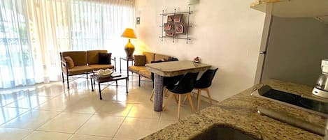 A modern kitchen with a granite countertop and a built-in sink, adjacent to a dining area with a table and chairs.