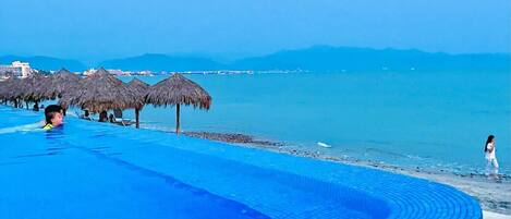 A infinity pool with a view of the sea and mountains.