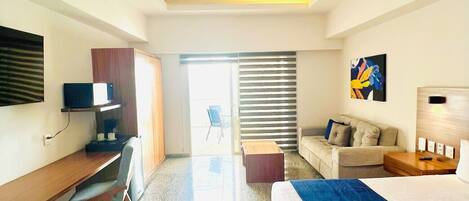 A hotel room with a bed, desk, chair, and a ceiling fan.
